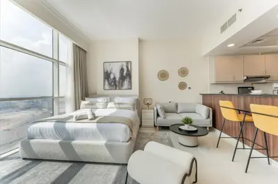 a bedroom with a large bed and a kitchen at Studio in Reef Residence JVC by PK Holidays in Dubai
