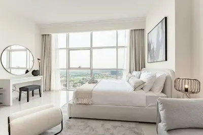 a white bedroom with a bed and a large window at Studio in Reef Residence JVC by PK Holidays in Dubai