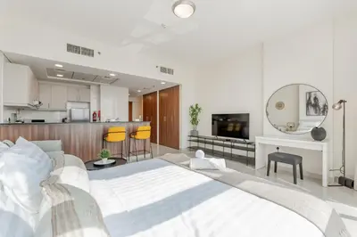 a bedroom with a large white bed and a kitchen at Studio in Reef Residence JVC by PK Holidays in Dubai