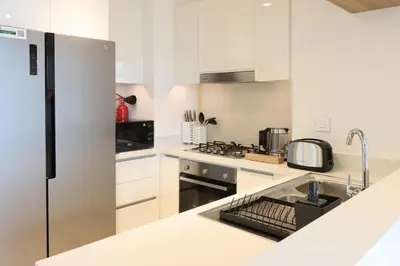 a kitchen with white cabinets and a stainless steel refrigerator at Livbnb Suites - Lavish 2BR w/ Burj Khalifa Views & Near Dubai Mall in Dubai
