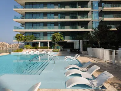 a swimming pool with white chairs and a building at Emaar Beachfront Beach Vista 3bdr apartment in Dubai
