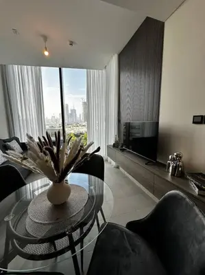 a living room with a glass table with a vase on it at Prime 1BR in Sobha Hartland, Burj Khalifa view in Dubai