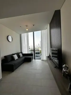 a living room with a black couch and a clock at Prime 1BR in Sobha Hartland, Burj Khalifa view in Dubai