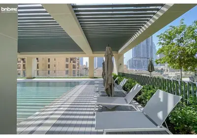 a pool with chairs and umbrellas on a building at bnbme - Chic 1BR Apt w Balcony Pool Gym Access Steps to Burj Khalifa & Dubai Mall in Dubai
