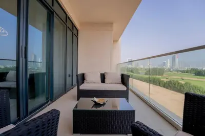 a balcony with a couch and a table and chairs at Lux Golf Views 3 BR in Emirates Hills in Dubai