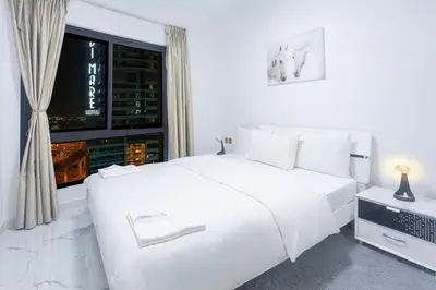 a white bedroom with a large white bed and a window at Luxury 2 Bedroom Apartment in Dubai Marina & JBR Beach in Dubai
