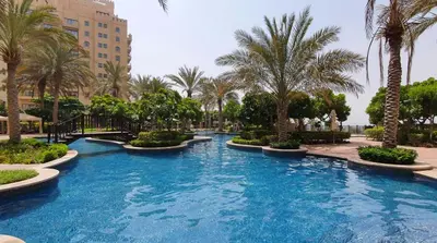a swimming pool with palm trees in a resort at Modern 1BR in Vibrant Fairmont North Residence - 90AB6 in Dubai