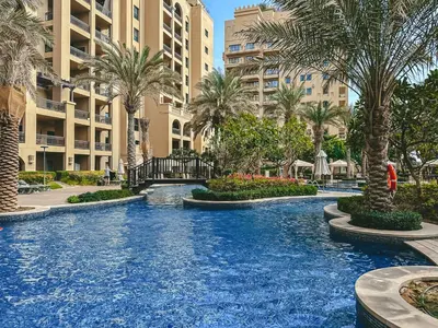 a resort swimming pool with palm trees and buildings at Modern 1BR in Vibrant Fairmont North Residence - 90AB6 in Dubai