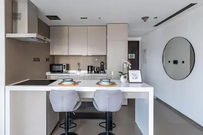 a kitchen with a white counter and two bar stools at GuestReady - Exquisite residence in Dubai Marina in Dubai