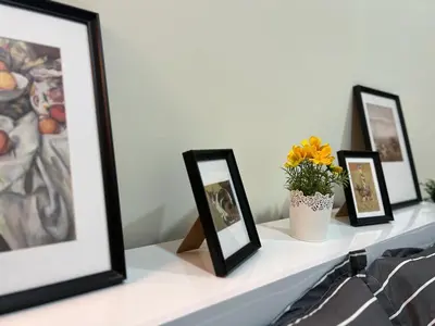 a shelf with three framed pictures and a vase of flowers at Beautiful Bedroom in Al Barsha Near Mashreq Metro in Dubai