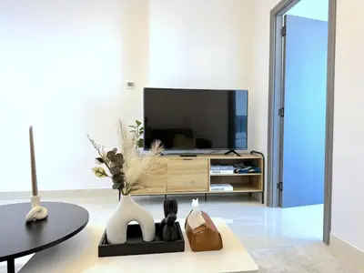 a living room with a television and a table at Deluxe Apartment With Panoramic View Near Metro in Dubai