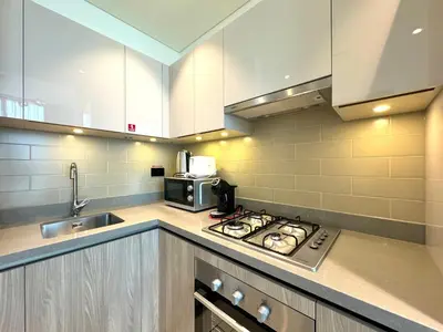a kitchen with a stove top oven next to a sink at Stylish brand new 1 bedroom in Dubai