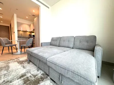 a gray couch in a living room with a table at Stylish brand new 1 bedroom in Dubai