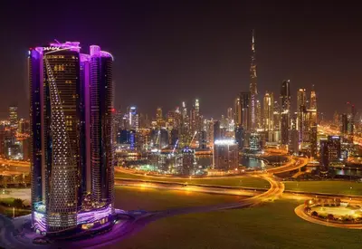a lit up city at night with cars at Paramount Towers - Elegant Home in Dubai
