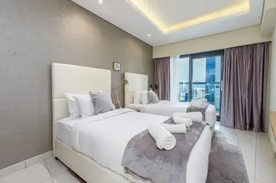 two beds in a hotel room with a large window at Paramount Towers - Elegant Home in Dubai