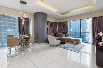 a living room with a table and chairs and a couch at Paramount Towers - Elegant Home in Dubai