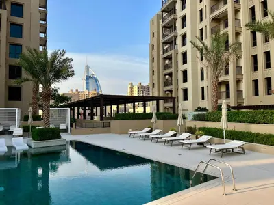 a swimming pool with lounge chairs and a building at Brand new 2 Bedroom apartment in Madinat Jumeirah Living in Dubai