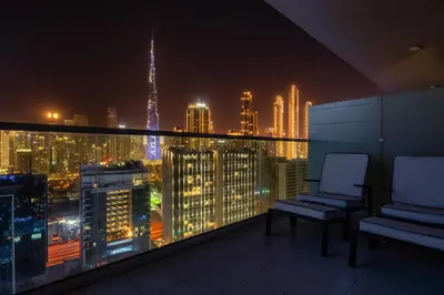 a balcony with two chairs and a city skyline at night at Luxury Top Floor, with full Burj Khalifa View in Dubai
