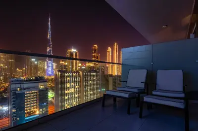 two chairs on a balcony with a city skyline at night at Luxury Top Floor, with full Burj Khalifa View in Dubai