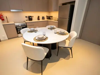 a kitchen with a table with chairs and a refrigerator at MH - Act One Act Two - 2BHK - REF503 in Dubai