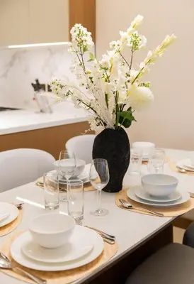 a table with plates and glasses and a vase of flowers at EDEN'S Homes & Villas - Address Opera District Residences in Dubai