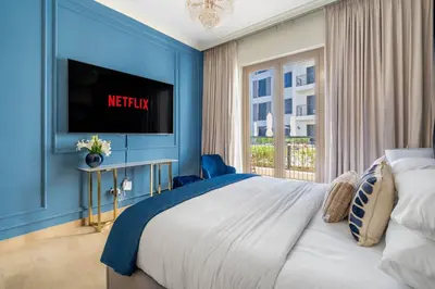a bedroom with a large bed and a tv at GuestReady - Stylish blue elegance in La Cote in Dubai