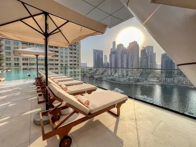 a row of lounge chairs on a balcony with a view of a city at GuestReady - Opulent Residence in Dubai Marina in Dubai