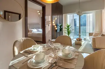 a dining room with a table and chairs and a living room at Stylish Stayz 2BR Corner Unit - Yacht & Burj Khalifa Views - close to Dubai Mall in Dubai