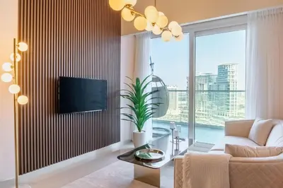 a living room with a couch and a tv on a wall at Stylish Stayz 2BR Corner Unit - Yacht & Burj Khalifa Views - close to Dubai Mall in Dubai