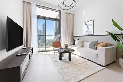 a living room with a white couch and a tv at Silkhaus Upscale 1BR by Burj Khalifa with Balcony in Dubai
