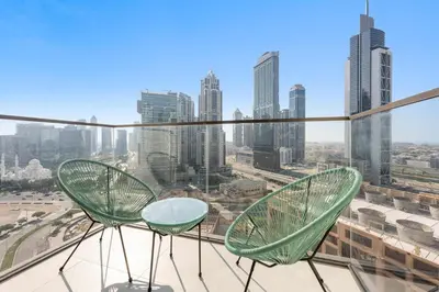 two green chairs on a balcony with a city skyline at Silkhaus Upscale 1BR by Burj Khalifa with Balcony in Dubai