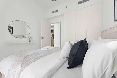 a white bedroom with a large bed and a mirror at Silkhaus Upscale 1BR by Burj Khalifa with Balcony in Dubai