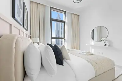 a white bedroom with a large white bed with pillows at Silkhaus Upscale 1BR by Burj Khalifa with Balcony in Dubai