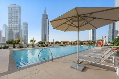 a pool with a chair and an umbrella at Silkhaus Upscale 1BR by Burj Khalifa with Balcony in Dubai
