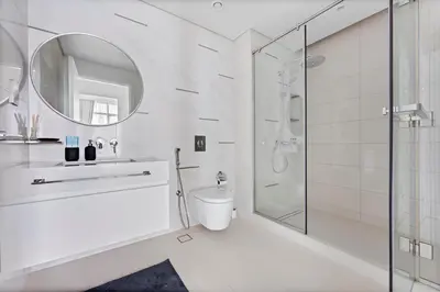 a white bathroom with a toilet and a shower at StoneTree - New Luxury Apartment with Private Beach in Dubai