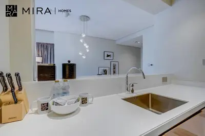 a white kitchen with a sink and a counter at Mira Holiday Homes - Furnished 1 bedroom in Paramount Tower B in Dubai