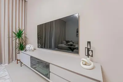 a living room with a large television on a white wall at NEW Luxe 3BR in Vida Marina w/ Breathtaking Views in Dubai