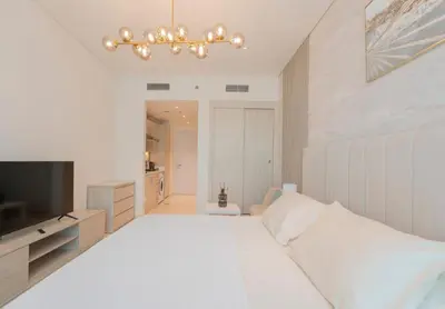 a white bedroom with a large bed and a television at Luxury Studio, Seven Palm Residence-Palm Jumeirah in Dubai