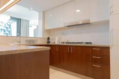 a large kitchen with wooden cabinets and a sink at FIRST CLASS 3BR with full BURJ KHALIFA and FOUNTAIN VIEW in Dubai