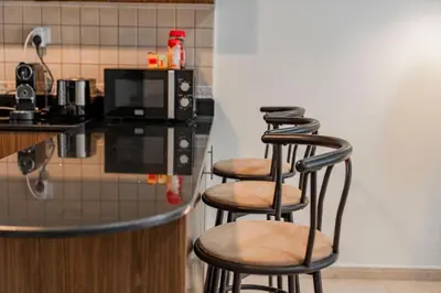 a kitchen with three bar stools in front of a microwave at Stunning 1 BR Apartment in Dubai Marina in Dubai