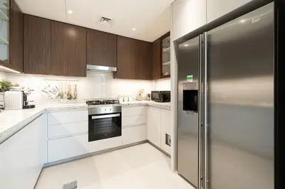 a kitchen with white cabinets and a stainless steel refrigerator at Magnificent Cozy 2BR in Downtown Dubai in Dubai