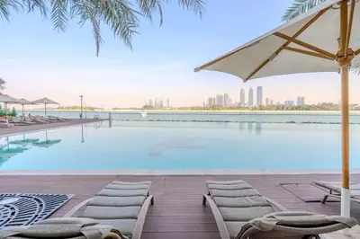 a swimming pool with chairs and an umbrella at GuestReady - Glamourous living in Palm Jumeirah in Dubai