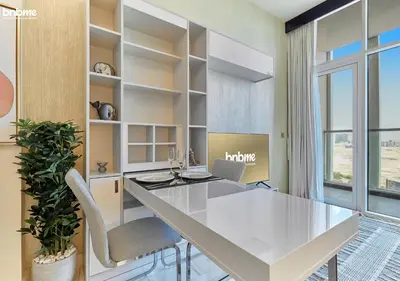an office with a white table and chairs and a laptop at bnbmehomes - Bayz by Danube in Dubai