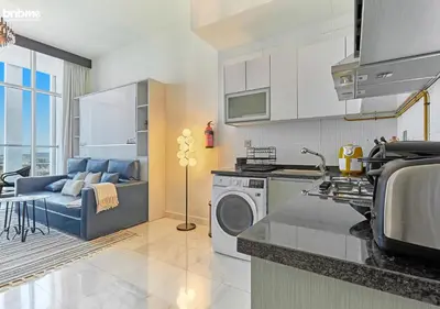 a kitchen with a washing machine and a living room at bnbmehomes - Bayz by Danube in Dubai