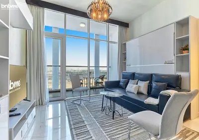 a living room with a blue couch and a large window at bnbmehomes - Bayz by Danube in Dubai