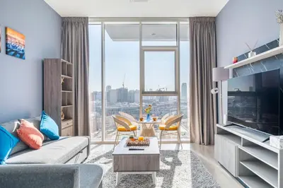 a living room with a couch and a table with chairs at Dubai Dreamland 1BR for 4, King Bed, Pool, Sauna, Gym, Free Parking in Dubai