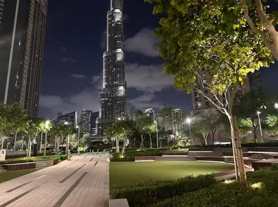 a view of a park at night with a tall building at Burj Khalifa view - Modern 1BDR apartment in Dubai