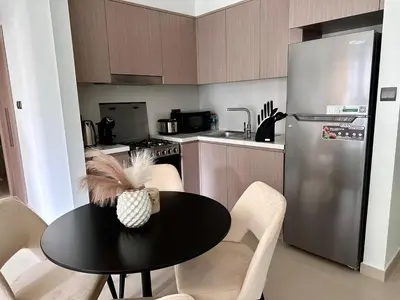a kitchen with a black table and a refrigerator at Burj Khalifa view - Modern 1BDR apartment in Dubai