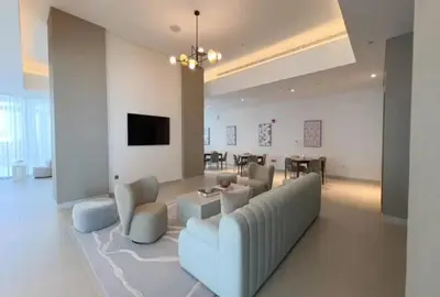 a living room with a couch and chairs and a tv at Modern 1 BR with Sea View - Minutes to Dubai Mall, Downtown Dubai in Dubai