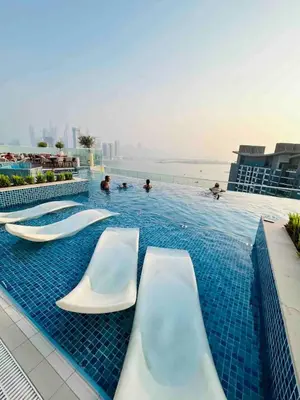 a swimming pool with chairs and people in the water at Modern Fully-Equipped Apartment in Seven Palm, Beach and Pool Access in Dubai